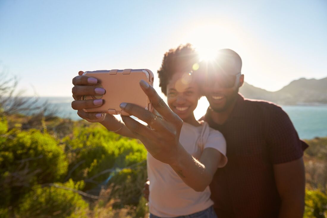 Smiling couple taking a selfie of them and an amazing view on vacation.