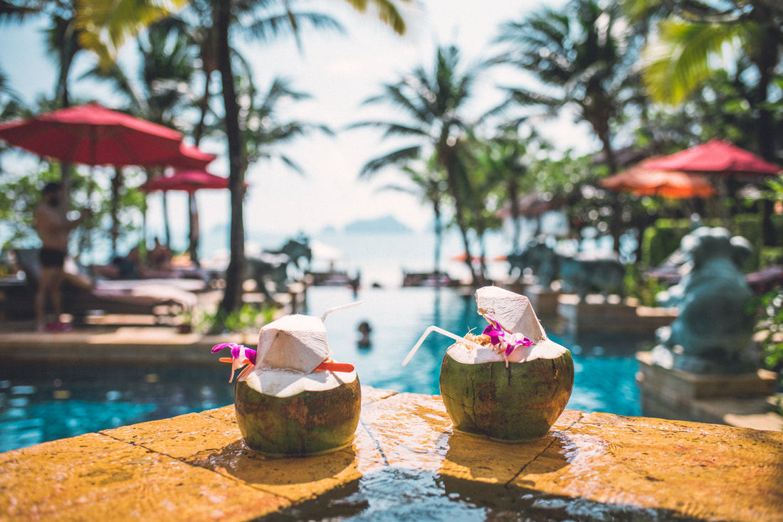 Fun coconut drinks with flowers by resort style pool looking over the ocean.